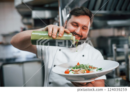 Giving oil to the salad. Professional chef preparing food in the kitchen 124039259