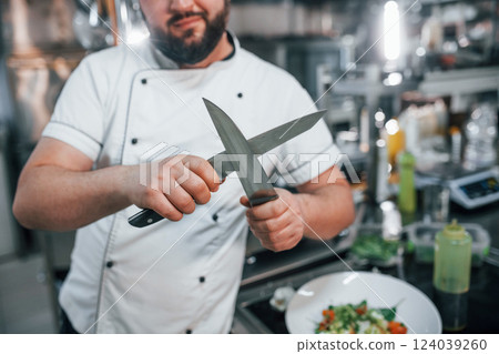 With sharp knives. Professional chef preparing food in the kitchen 124039260