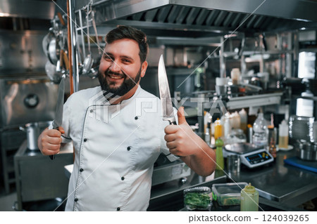 With sharp knives. Professional chef preparing food in the kitchen 124039265