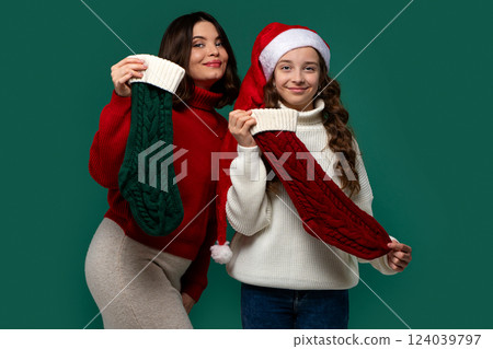Mum and teenage daughter hold red and green Christmas stockings Mum and teenage daughter hold red and green Christmas stockings 124039797