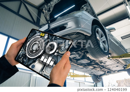 Serviceman with laptop checks engine in car service augmented reality 124040199