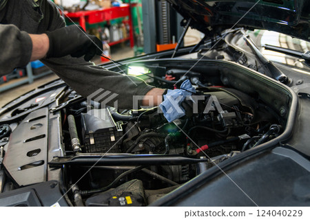 Serviceman checks the oil level in a car engine Serviceman checks the oil level in a car engine 124040229
