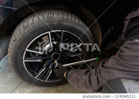 Serviceman checks car suspension on a column lift in car service. 124040231