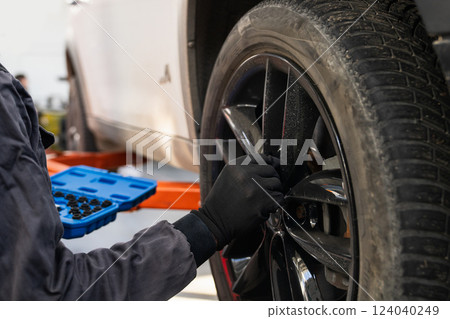 Serviceman checks car suspension on a column lift in car service. Serviceman checks car suspension on a column lift in car service. 124040249