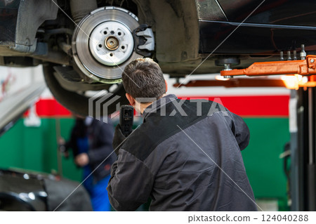 Serviceman checks the brake discs of a car Serviceman checks the brake discs of a car 124040288