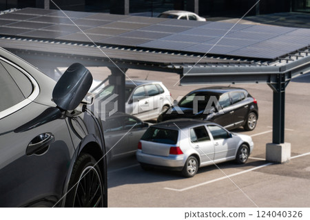 Electric car is charging from a charging station that takes energy from solar panels. Close up 124040326