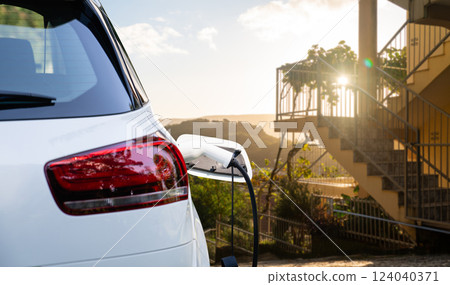 Close up of electric car inlet with a connected charging cable 124040371