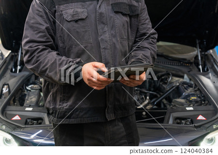 Serviceman with tablet checks car software in car service 124040384
