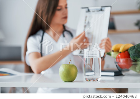 With document in hands. Professional medical worker in white coat is in the office With document in hands. Professional medical worker in white coat is in the office 124040468