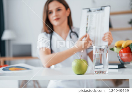 With document in hands. Professional medical worker in white coat is in the office 124040469