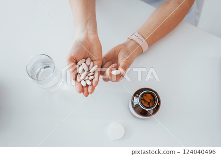 Top view of woman's hands that holding pills. Professional medical worker in white coat is in the office 124040496