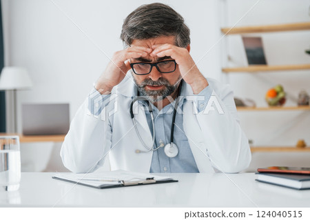 Man tired, have headache. Professional medical worker in white coat is in the office 124040515