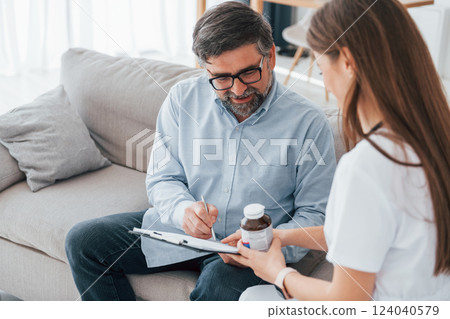 Giving prescription and pills. Professional nurse is in white coat is in the office 124040579