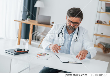 Man is busy with documents. Professional medical worker in white coat is in the office 124040586