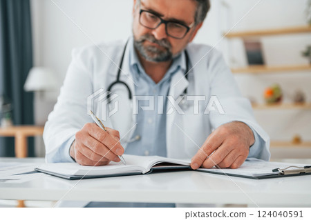 Man is working with documents. Mature doctor in white coat is in the office 124040591