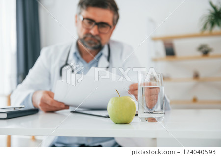 Man is working with documents. Mature doctor in white coat is in the office 124040593