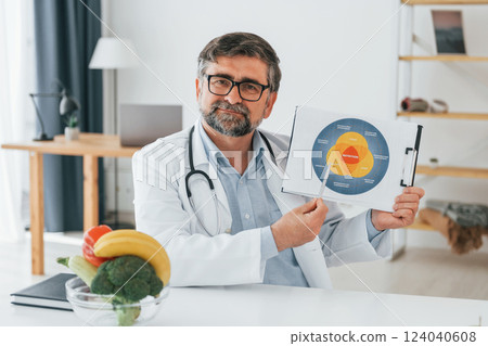 Holding dieting plan illustration. Professional medical worker in white coat is in the office Holding dieting plan illustration. Professional medical worker in white coat is in the office 124040608