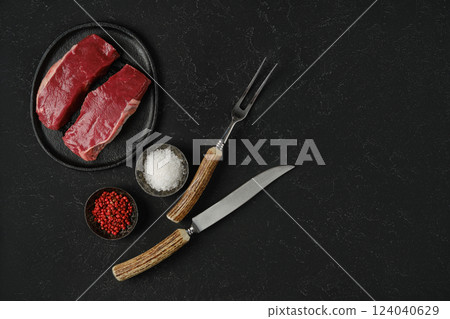 Preparing gourmet beef steak dinner with fresh ingredients on a dark textured surface 124040629