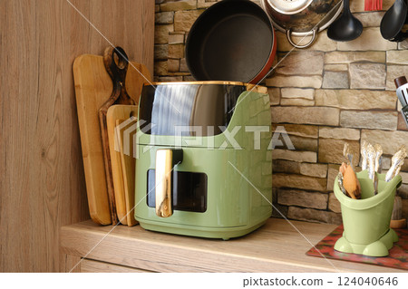 Stylish green air fryer on a kitchen counter against a stone wall backdrop Stylish green air fryer on a kitchen counter against a stone wall backdrop 124040646