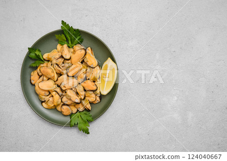 Mussels on a green plate with garnish and lemon wedge Mussels on a green plate with garnish and lemon wedge 124040667