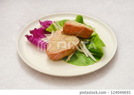 Delicious sesame-coated tuna fish served on a bed of fresh greens with vibrant vegetables 124040691