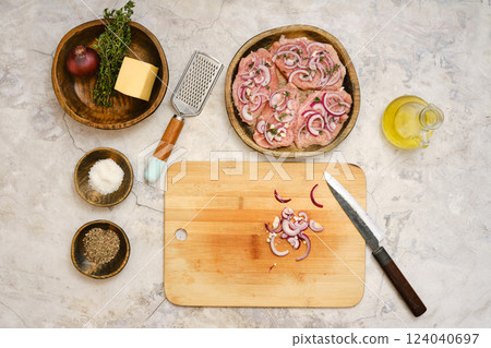 Preparing pork chops with onions and cheese on a wooden cutting board in a modern kitchen Preparing pork chops with onions and cheese on a wooden cutting board in a modern kitchen 124040697