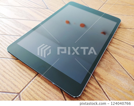 Sleek black tablet rests on a light wood table. The screen displays a blurred, out-of-focus image, creating a clean, modern aesthetic perfect for tech, business, or lifestyle projects. Sleek black tablet rests on a light wood table. The screen displays a blurred, out-of-focus image, creating a clean, modern aesthetic perfect for tech, business, or lifestyle projects. 124040766