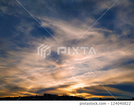 Dramatic sunset sky with layered clouds and silhouetted hills. 124040822