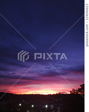 Dramatic twilight sky ablaze with vibrant hues of purple, pink, and orange.  Perfect for backgrounds, website headers, or atmospheric mood pieces. Evokes feelings of serenity and wonder. 124040823