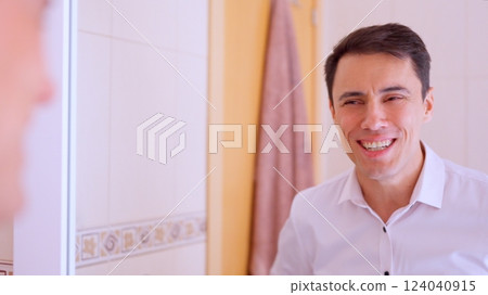 Optimistic businessman smiling at reflection in bathroom mirror Optimistic businessman smiling at reflection in bathroom mirror 124040915