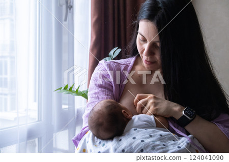 Mother Breastfeeding Baby by Window 124041090