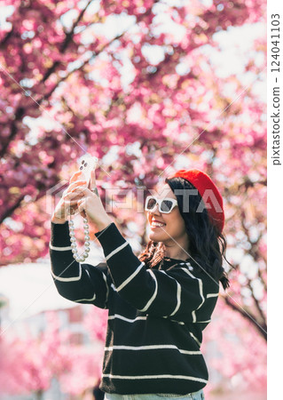 happy woman taking selfie on the phone in front of blooming sakura happy woman taking selfie on the phone in front of blooming sakura 124041103