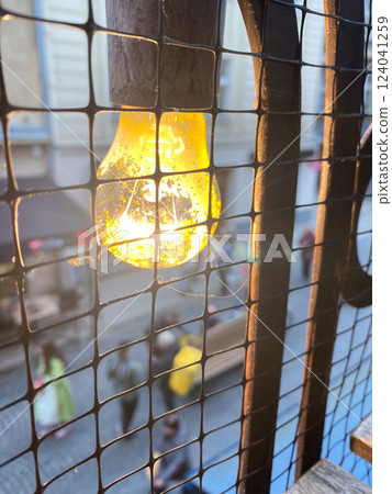 Glowing Light Bulb Behind Wire Mesh Glowing Light Bulb Behind Wire Mesh 124041259