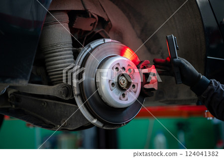 Serviceman checks the brake discs of a car Serviceman checks the brake discs of a car 124041382