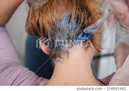 Woman applying blue hair dye with brush at home Woman applying blue hair dye with brush at home 124041482
