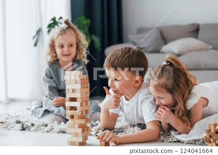 Playing wooden tower game. Group of children is together at home at daytime 124041664