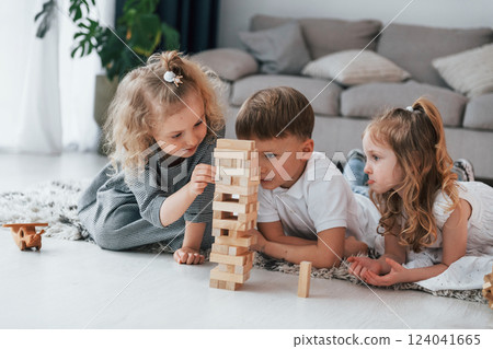 Playing wooden tower game. Group of children is together at home at daytime 124041665