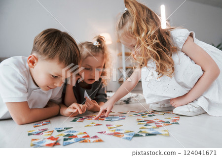 Sitting on the floor and playing game. Group of children is together at home at daytime 124041671