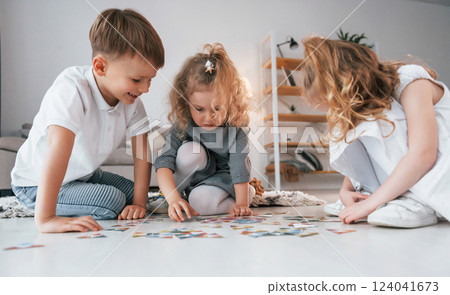 Sitting on the floor and playing game. Group of children is together at home at daytime 124041673