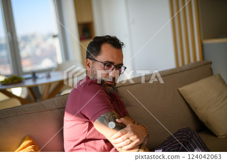Handsome man checking his CGM sensor on arm. 124042063