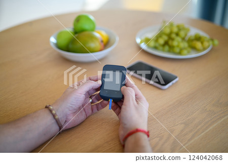 Diabetic man holding blood glucose meter to check blood sugar. 124042068