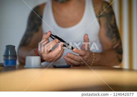 Diabetic man checking his blood sugar at home. 124042077