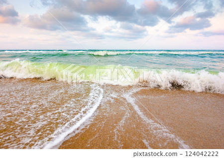 nature background with sea tide. beautiful seaside. water surface motion at storm. wave splash with foam on the wet beach. summer outdoor weather with wind. beautiful view of travel wallpaper with 124042222