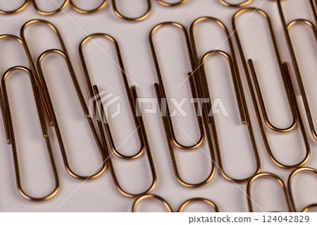 large  sized copper paper clips lie on white blank paper 124042829