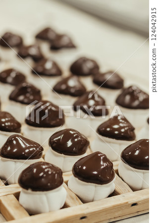 Marshmallow sweets in the form of mushroom in wooden tray on industry. Brown-white boletus. 124042915