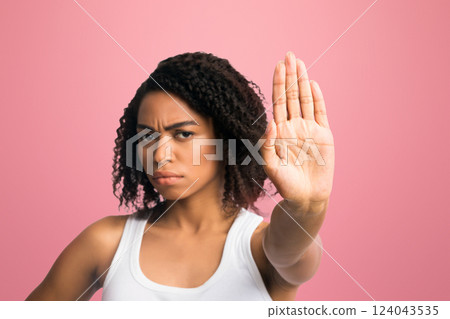 Stop It. Portrait of serious black woman standing with outstretched hand showing stop gesture isolated over white wall Stop It. Portrait of serious black woman standing with outstretched hand showing stop gesture isolated over white wall 124043535
