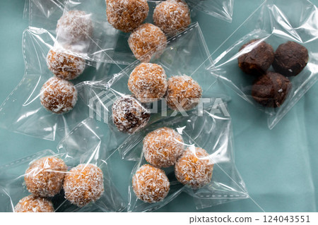 Delicious coconut and chocolate balls in clear packaging on blue background 124043551