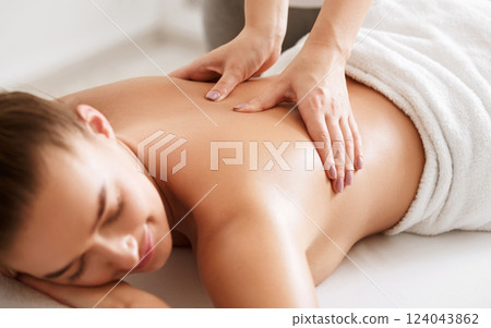 Young girl receiving back massage with closed eyes in spa center, closeup 124043862