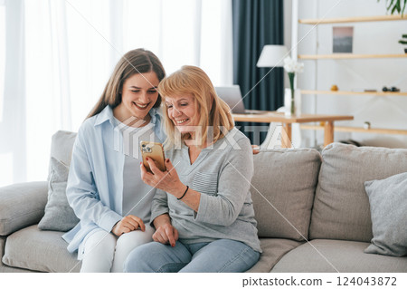 Using smartphone. Mother and daughter is together at home 124043872