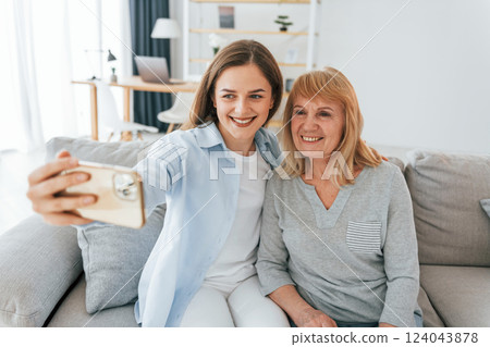 Making selfie by using smartphone. Mother and daughter is together at home Making selfie by using smartphone. Mother and daughter is together at home 124043878